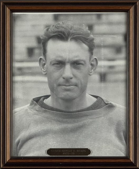 Black-and-white portrait of Ernest Bearg in a sweatshirt on the practice field.