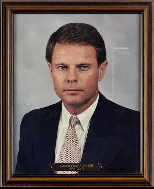 Colour portrait of Frank Solich in a navy suit and gold tie.