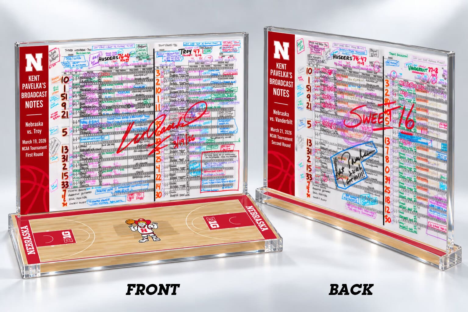 One double-sided display, photographed from both sides and labelled FRONT and BACK. Each face holds a broadcast spotting board in clear acrylic beside a scarlet panel carrying the Nebraska N, “Kent Pavelka’s Broadcast Notes”, the opponent, the date and the tournament round. The front is the Troy game, Huskers 76–47, signed across the sheet in red and dated; the back is Vanderbilt, Huskers 74–72, with “Sweet 16” written across it in red and Kent’s signature boxed in blue. It stands on a base finished as a Nebraska basketball floor — pale maple boards, scarlet keys, Big Ten marks, NEBRASKA along both side rails and Herbie at centre court.