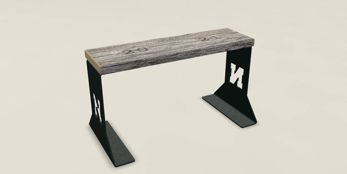 A bench built from Memorial Stadium bleacher wood on black steel feet cut with the Nebraska N.
